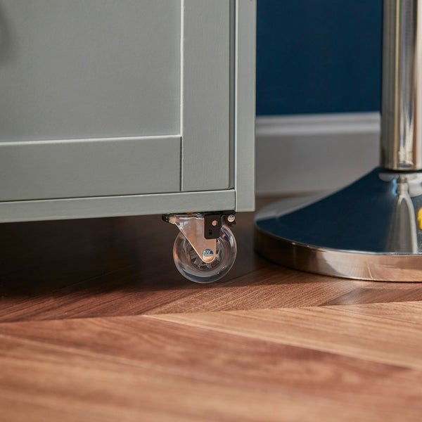 Detailaufnahme eines grauen Möbels mit transparenter Rolle auf einem Holzboden