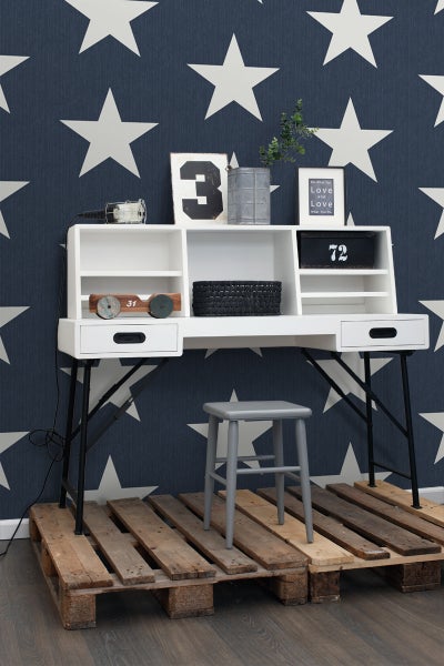 Schreibtisch mit Regalen und einem Hocker auf einer Holzpalette vor einer Tapete mit Sternenmuster.