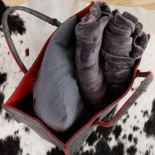 Filztasche mit zwei Tragegriffen befüllt mit einem Dekokissen und einer weichen Kuscheldecke.