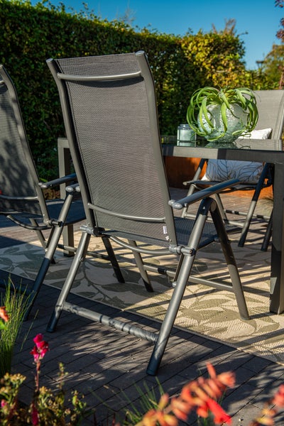 Garten-Hochlehner mit Aluminiumrahmen und Textilgewebe auf einer sonnigen Terrasse mit Tisch, Outdoorteppich und Pflanzen.