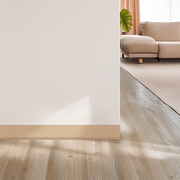 Helle Fußleiste an einer Wand in einem modern eingerichteten Wohnzimmer mit Holzoptikboden.