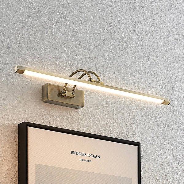 Bilderleuchte in Altmessing-Optik, montiert an einer strukturierten Wand über einem Bild.