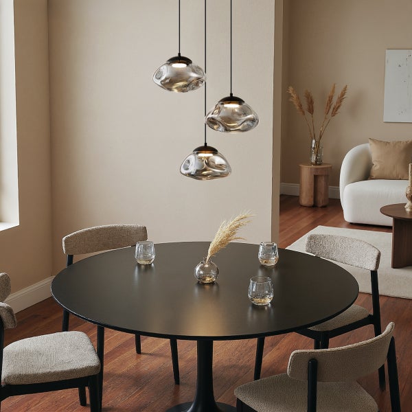 Esszimmer mit rundem Tisch, Stühlen und dreiflammiger Pendelleuchte