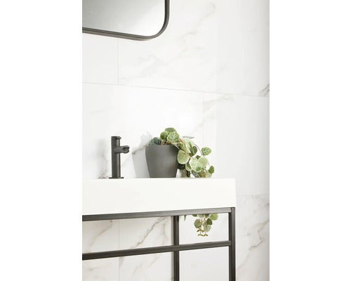 Modernes Badezimmer mit Waschbecken, Armatur, Spiegel und Wandfliesen in Marmoroptik.
