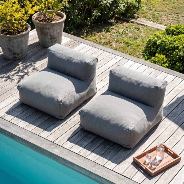 Zwei graue Outdoor-Sitzsäcke auf einer Holzterrasse am Pool mit Blumentöpfen und einem Serviertablett.