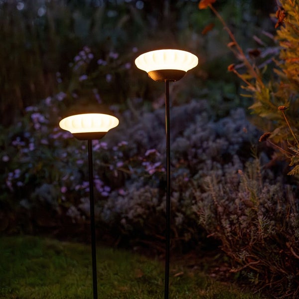 Zwei Gartenleuchten auf einer Rasenfläche im Freien.