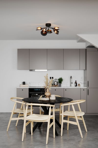 Helle, moderne Küche mit Esstisch und Stühlen unter einer Deckenleuchte