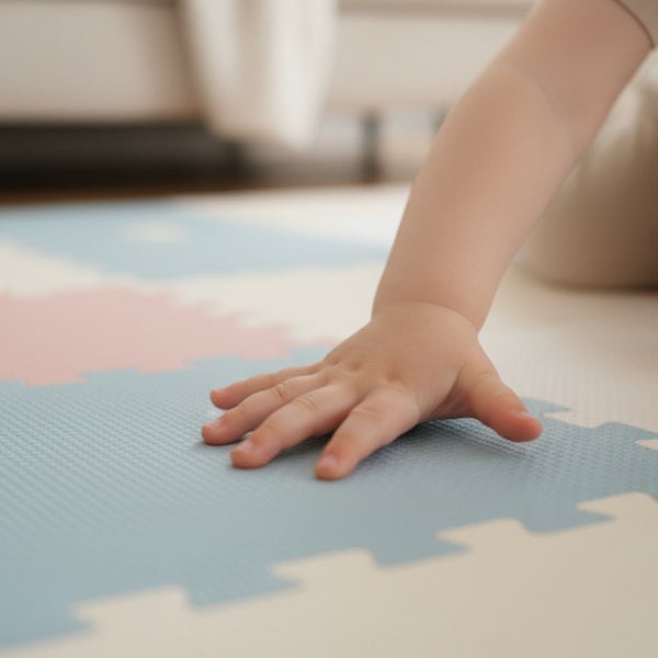 Hand eines Kindes auf einer weichen Puzzlematte aus Schaumstoff mit ineinandergreifenden Teilen.