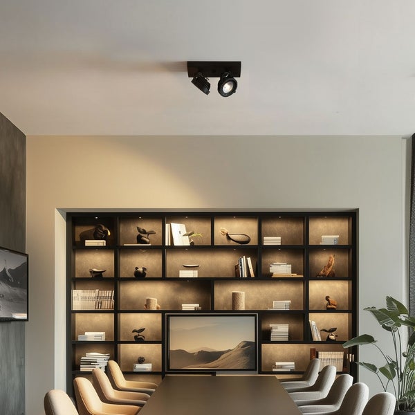 Moderne Deckenstrahler an einer Zimmerdecke über einem eleganten Essbereich mit beleuchtetem Regal und stilvoller Einrichtung.