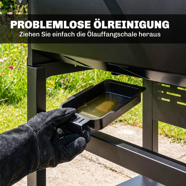 Eine Hand in einem Hitzeschutzhandschuh zieht die Ölauffangschale zur einfachen Reinigung aus einem Grill heraus.