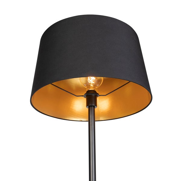 Stehleuchte mit schwarzem Textilschirm, goldener Innenseite und sichtbarem Leuchtmittel.