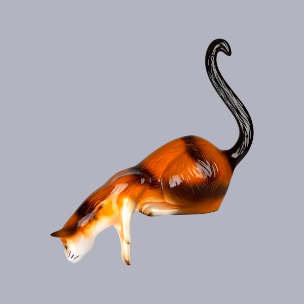 Dekofigur Katze aus glänzender Keramik, kauernde Pose mit langem, geschwungenem Schwanz.