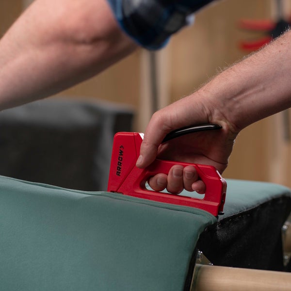 Handtacker von Arrow wird verwendet, um Stoff auf ein Werkstück aus Holz zu heften.