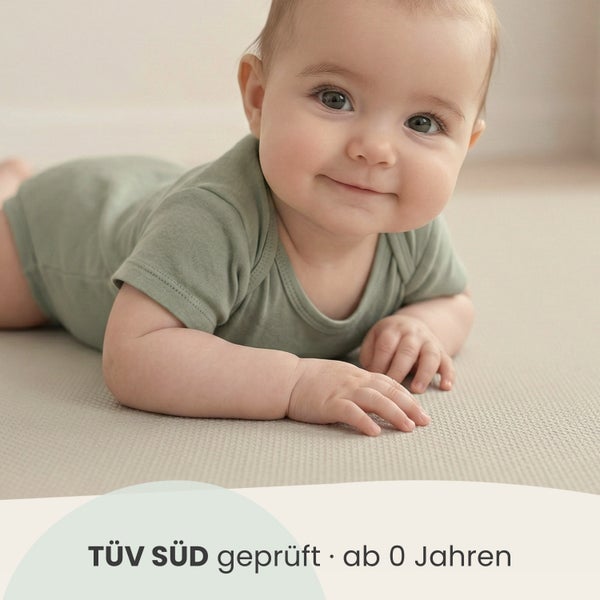 Ein Baby liegt auf einer strukturierten Bodenmatte. Text: TÜV SÜD geprüft, geeignet ab null Jahren.