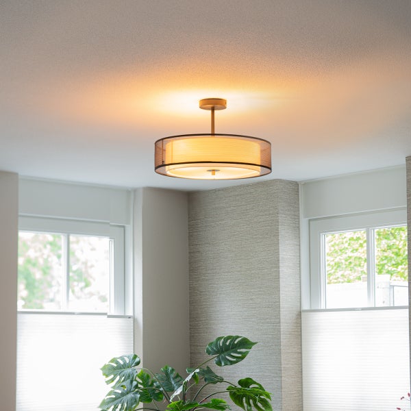 Moderne Deckenleuchte mit doppeltem Rundschirm und Textildiffusor in einem hellen, modern eingerichteten Raum mit Zimmerpflanzen.