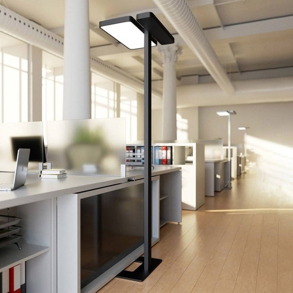 Moderne schwarze LED-Stehleuchte mit zwei Paneelen in einem hellen, organisierten Büro mit Schreibtischen und Holzboden.