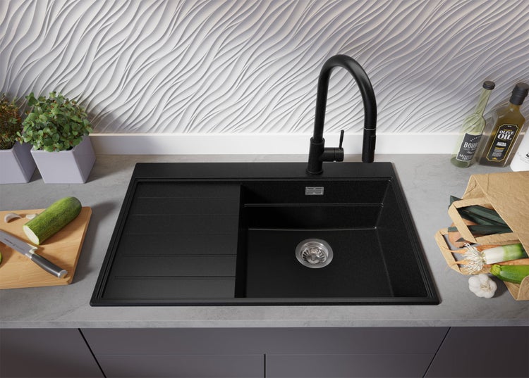 Schwarze Küchenspüle mit Abtropffläche und Wasserhahn auf Arbeitsplatte