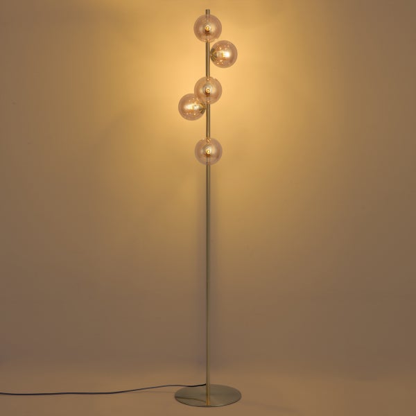 Moderne Stehlampe mit fünf gläsernen Leuchtkugeln an einem schlanken Metallgestell für ein Wohnzimmer.