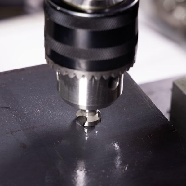 Senkbohrer in einem Bohrfutter beim Bohren in eine Metallplatte.