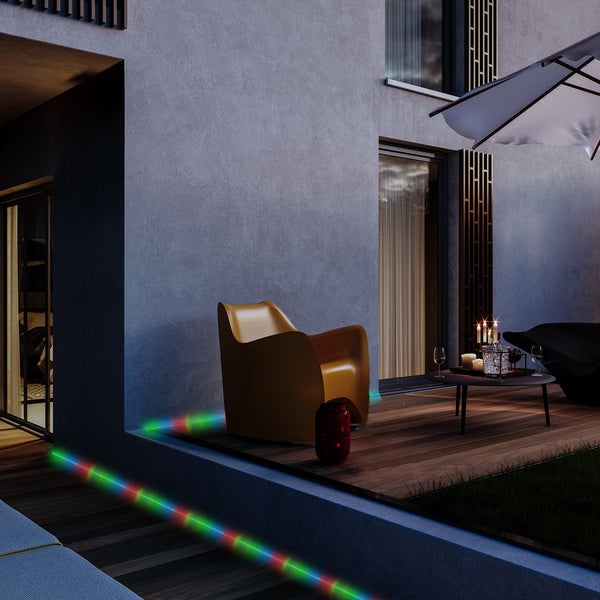 Moderne Terrasse bei Nacht mit Holzdeck, gelbem Sessel und farbigen LED-Lichtstreifen zur Akzentbeleuchtung an den Kanten.