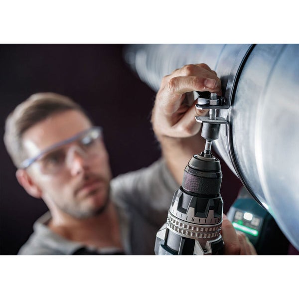 Ein Mann befestigt ein Rohr mit einem Akkuschrauber.