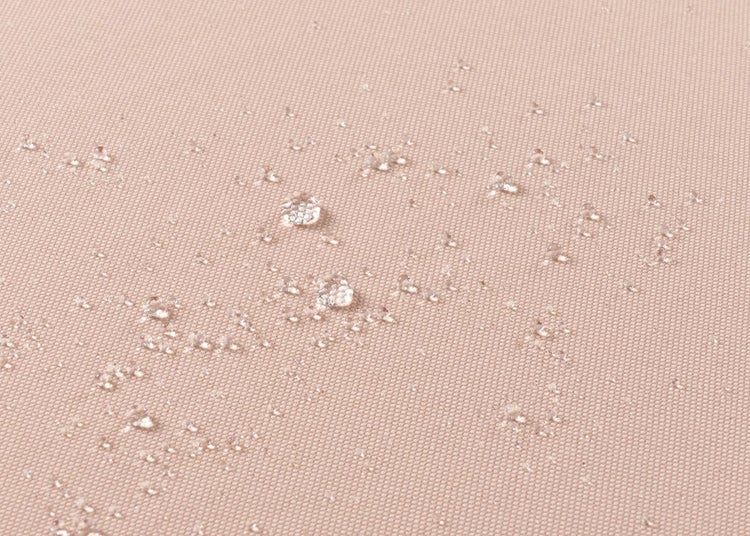 Nahaufnahme eines wasserabweisenden Stoffes mit abperlenden Wassertropfen.