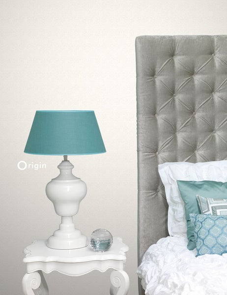 Dekoratives Schlafzimmer mit Lampe auf einem Nachttisch und gestepptem Kopfteil.