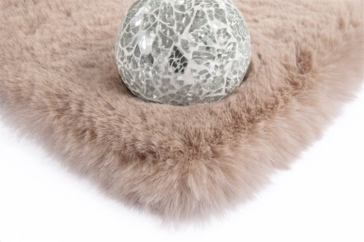 Weicher Kunstfellteppich mit dichter Struktur und dekorativer Mosaikkugel aus Glas.