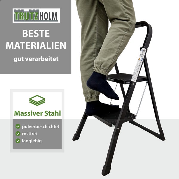 Eine zweistufige Trutzholm Trittleiter aus pulverbeschichtetem Stahl mit einer Person, die auf der Leiter steht.