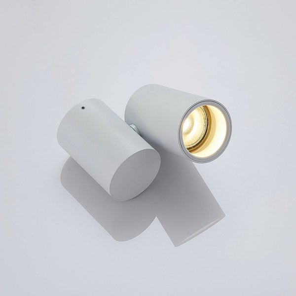 Zwei zylinderförmige Wandleuchten aus Metall, eine davon leuchtet.