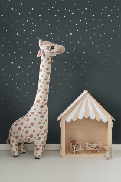 Szene mit Stoffgiraffe, Spielhaus, Puppenmöbeln und Spielzeugmäusen vor einer mit Sternenmustern versehenen Wand