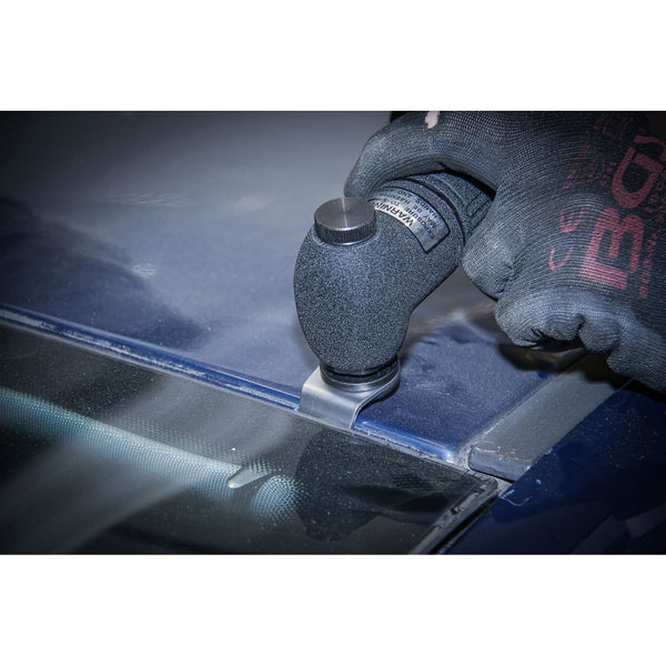 Eine Hand mit Handschuh bedient ein Scheibenentfernungs-Werkzeug von BGS auf einer blauen Motorhaube.