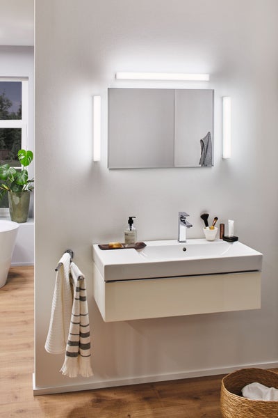 Modernes Badezimmer mit hängendem Waschtischunterschrank, Keramikwaschbecken, Chrom-Armatur und rechteckigem Spiegel mit LED-Beleuchtung.