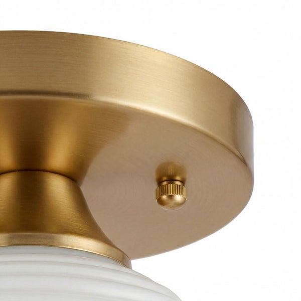 Detailansicht der Deckenhalterung einer Leuchte aus gebürstetem Messing mit weißem Glasschirm.