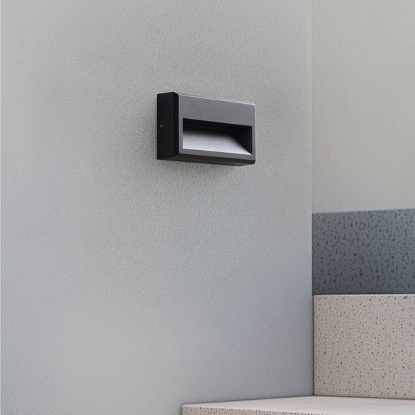 Anthrazitfarbene rechteckige Wandleuchte in modernem Design an einer strukturierten Wand neben Treppenstufen aus Stein.