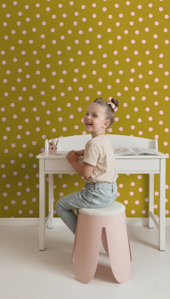 Vlies-Tapete mit rosa Punkten auf olivfarbenem Grund im Kinderzimmer mit Kind an einem weißen Schreibtisch.