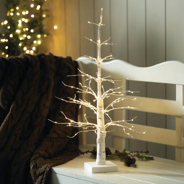 Beleuchteter Deko Baum in Birkenoptik mit LED Lichterkette auf einem weißen Sockel als stimmungsvolle Weihnachtsdekoration.