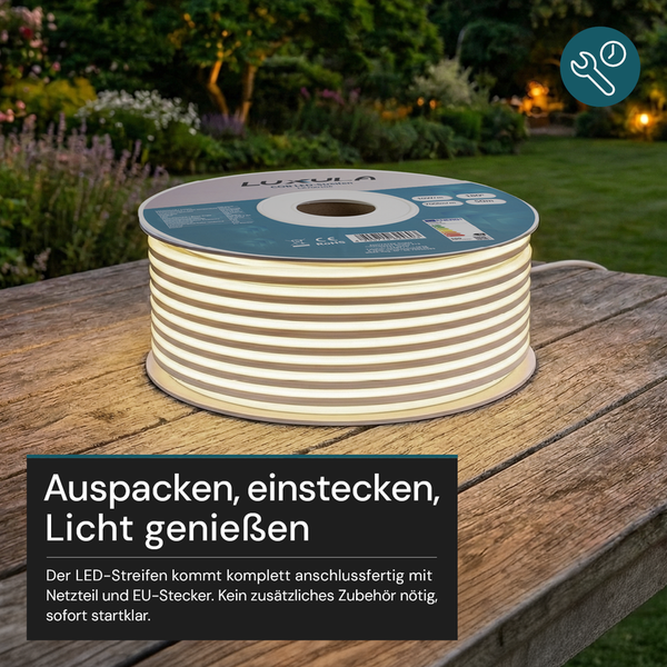 Leuchtender LED-Streifen auf einer Rolle auf einem Holztisch im Garten, inklusive Netzteil und europäischem Stecker, sofort einsatzbereit.