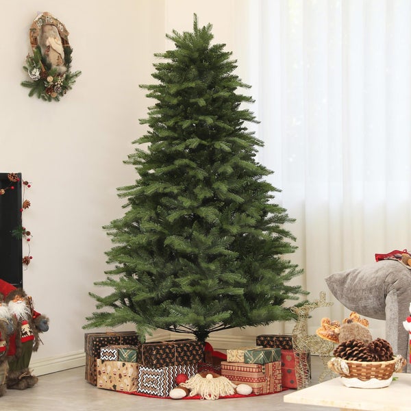 Großer, grüner künstlicher Weihnachtsbaum in einem hellen Wohnzimmer mit Geschenken und Weihnachtsdekoration.