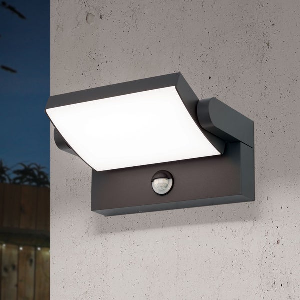 Moderne Außenwandleuchte mit Bewegungsmelder und verstellbarem LED-Panel an einer Betonwand.