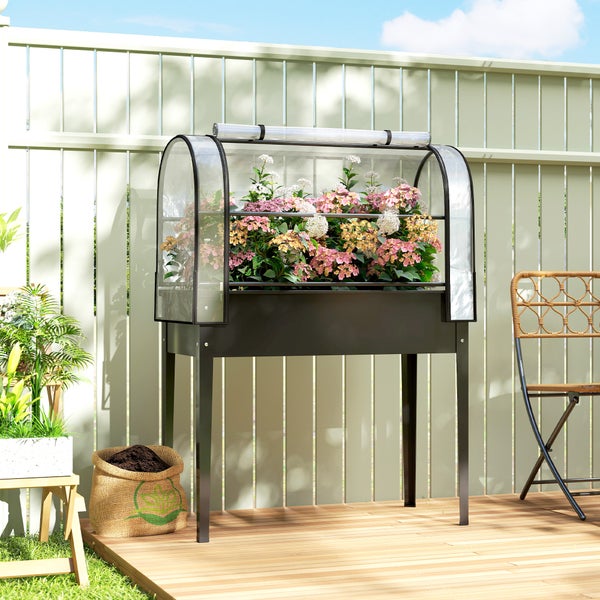 Hochbeet aus Metall mit transparentem Frühbeetaufsatz, bepflanzt mit Hortensien auf einer Holzterrasse vor einem Zaun.