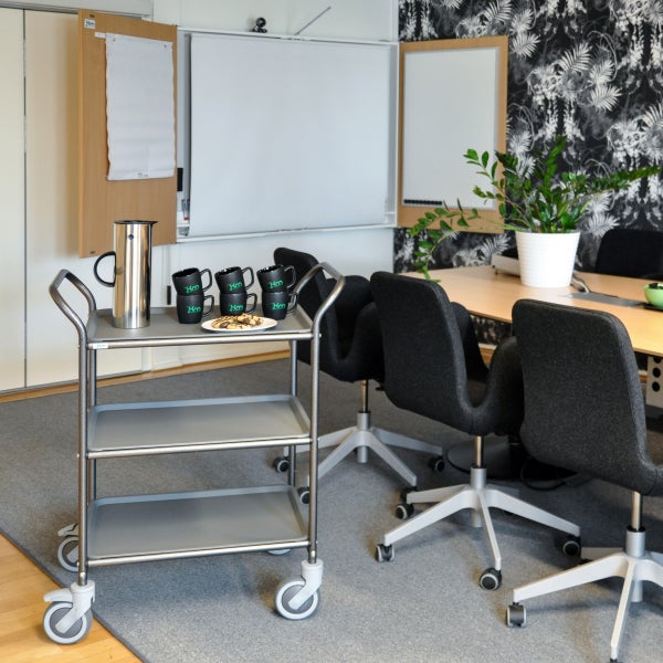 Szene eines Konferenzraums mit Servierwagen, Kaffeekanne, Tassen, Keksen, Stühlen, Tisch und Büropflanze