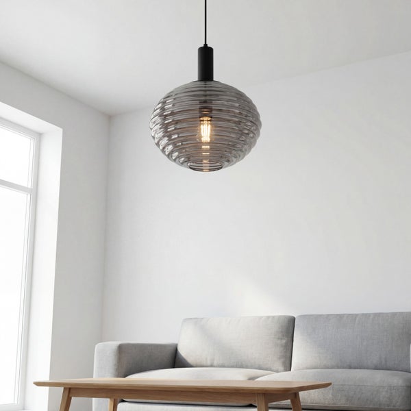 Moderne Hängeleuchte mit geriffeltem Schirm aus Rauchglas über einem grauen Sofa und Holztisch in einem hellen Wohnzimmer.