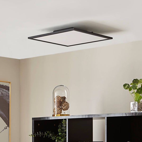 Quadratische LED-Deckenleuchte in flachem Design, montiert an einer Decke über einem Regal mit Dekorationsgegenständen.