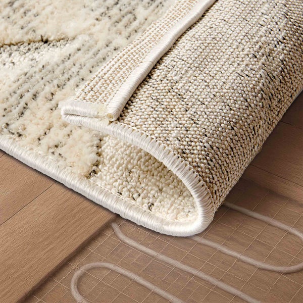Detailansicht eines beigen Teppichs mit Muster auf einem Holzboden mit Fußbodenheizung.