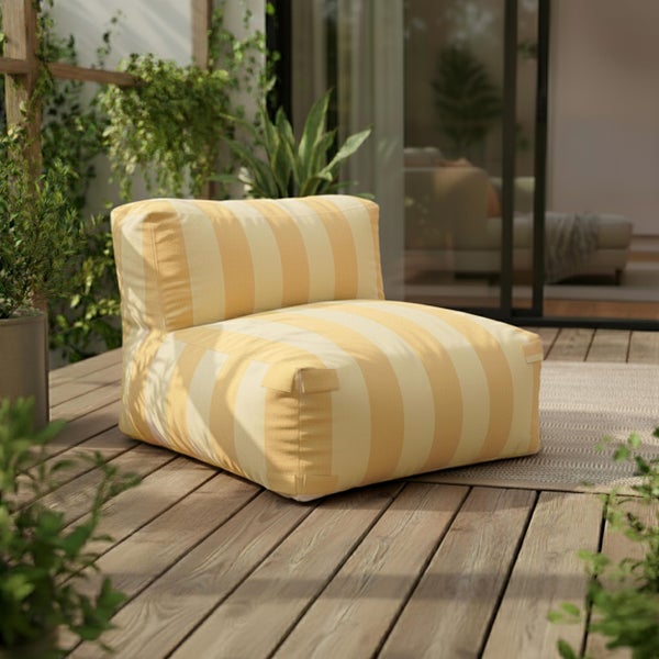 Gestreifter Outdoor-Sitzsack auf einer Holzterrasse mit Pflanzen und einer Glasfront im Hintergrund in heller Atmosphäre.
