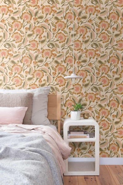 Schlafzimmer mit floraler Mustertapete, Holz-Kopfteil, weißem Nachttisch, Bettwaren und Hängeleuchte.