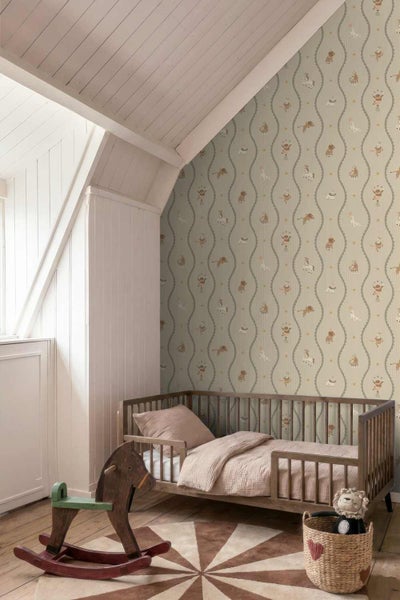 Vliestapete für das Kinderzimmer mit Tiermotiven und Wellenmuster an einer Wand hinter einem Kinderbett aus Holz.