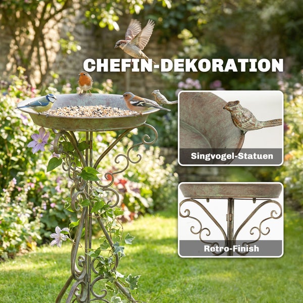 Vogeltränke aus Metall mit Retro-Finish und Singvogel-Statuen auf einem verzierten Ständer in einem Garten.