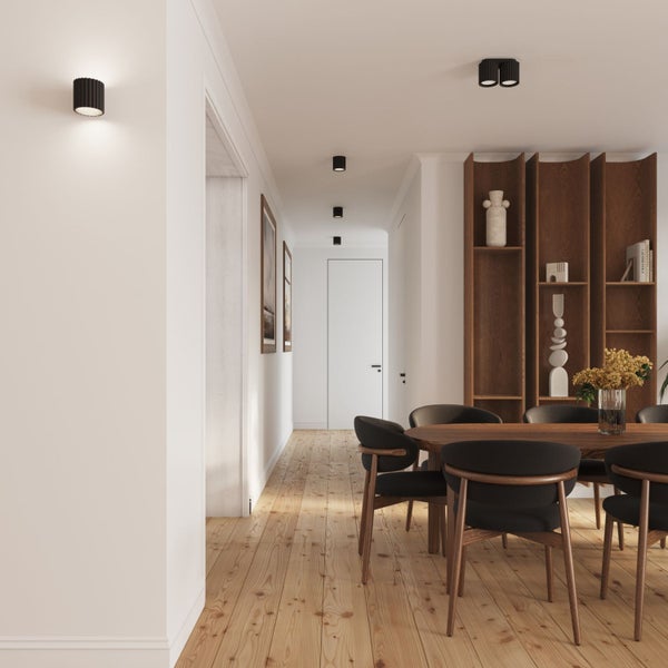 Moderner Essbereich und Flur mit Holzfußboden, schwarzen Deckenstrahlern, Wandleuchte, Holztisch, schwarzen Stühlen und großem Holzregal.